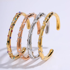 Detail van diverse gouden en zilveren open armbanden met parels en gekleurde kristallen