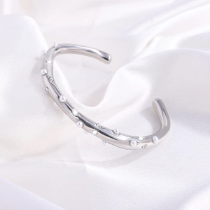 Detail van een gepolijste zilveren open armband met glanzende parels en zirkonia-stenen