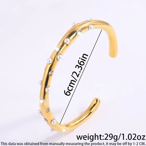 Detail van gouden armband met een diameter van 6cm, witte parels en ingelegde kristallen
