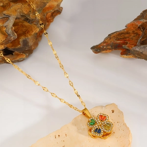 Detail shot of four-leaf clover necklace with colorful gems on a natural stone base
