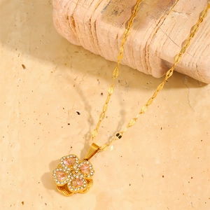 Detail of clover pendant with pink crystal and tiny white stones on wavy gold chain