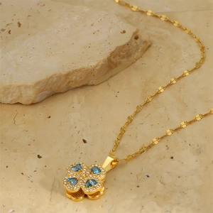 Detailed close-up of golden clover pendant featuring blue teardrop gems and small diamonds