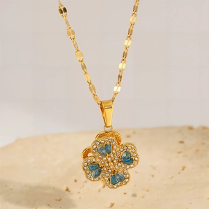 Detail of rotating four-leaf clover pendant with blue zircon stones and 18k gold plating