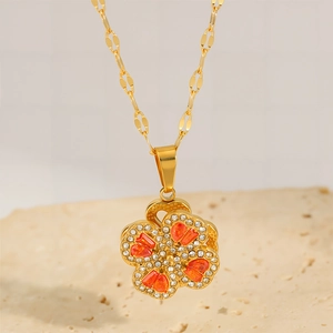 Rotating four-leaf clover pendant necklace in 18k gold plated steel with orange crystals