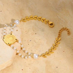 Detail eines Gold-Titanstahl-Armbands mit St. Benedikt-Medaille und Perlen-Ebenen