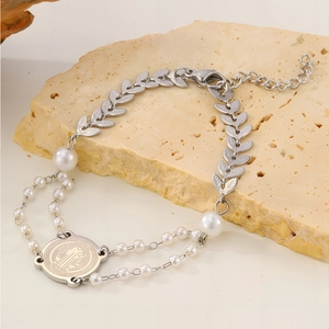 Nahaufnahme einer Benedikt-Medaille an einem zweireihigen Perlenarmband aus Edelstahl
