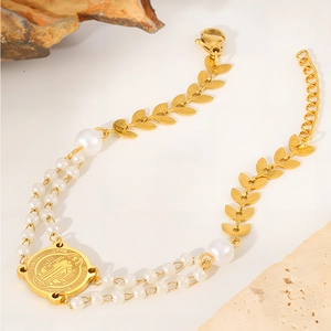 Detailansicht eines Gold Titan-Armbands mit Perlen Blattanhängern und Benediktus-Medaille
