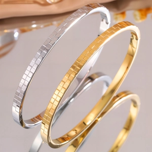 Vista macro di braccialetti in acciaio al titanio oro e argento con trama a scacchi