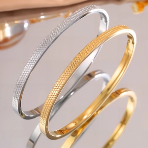 Dettaglio macro di bracciali in titanio oro e argento con trama geometrica a nido d'ape