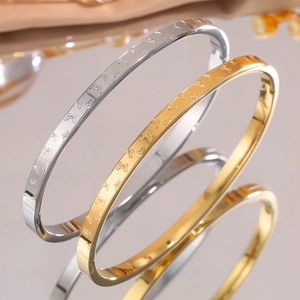 Dettaglio di bracciali in acciaio al titanio oro e argento con motivi a farfalla e fibbie