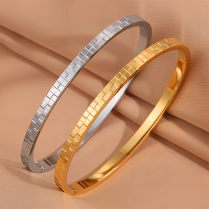 Dettaglio dei bracciali rigidi testurizzati oro e argento su tessuto di raso