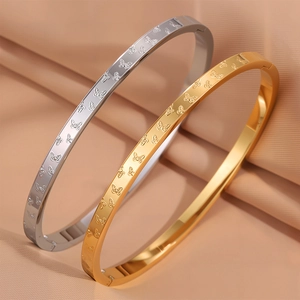 Dettaglio di bracciali in acciaio al titanio oro e argento con incisione a farfalla