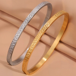 Primo piano di bracciali in acciaio al titanio oro e argento con motivo a mattoni a rilievo