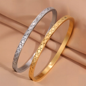 Dettaglio ravvicinato di bracciali geometrici in oro e argento con trama trapuntata