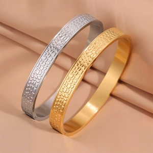 Dettaglio di bracciali in acciaio al titanio oro e argento con trama a coccodrillo