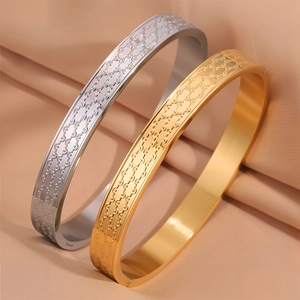Dettaglio di bracciali in acciaio al titanio oro e argento con motivi a onde su seta
