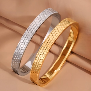 Vista macro di bracciali in acciaio oro e argento con incisione a trama a nido d'ape