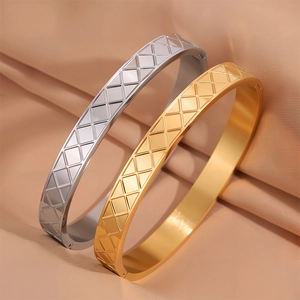 Dettaglio di bracciali in titanio oro e argento con trama geometrica a tratteggio su raso