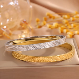 Dettaglio ravvicinato di bracciali in acciaio al titanio oro e argento con trama a nido