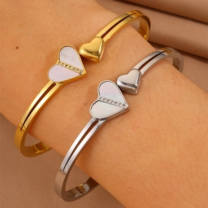 Gros plan de bracelets cœur or et argent avec nacre et petits strass brillants