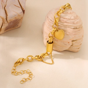 Close-up of golden chunky chain bracelet with polished heart pendant on mineral stone