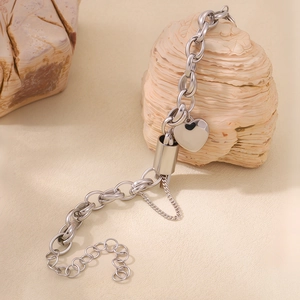 Close-up of a silver heart charm on a thick link bracelet with natural stone accents