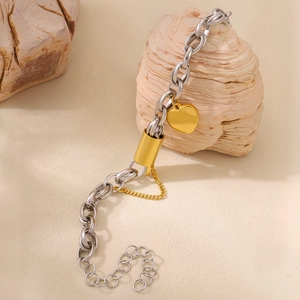 Close-up of thick silver chain bracelet with gold heart pendant and safety chain detail