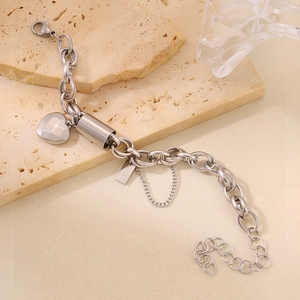 Detail of silver stainless steel chain bracelet with heart charm and cylinder pendant
