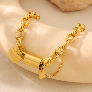 Golden stainless steel chain bracelet with heart and cylinder charms on display