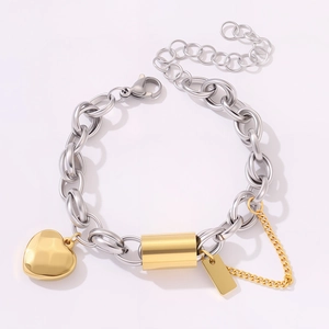 Detail of silver and gold mixed metal chain bracelet with heart charm and rectangular tag