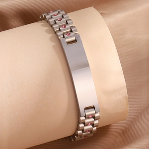 Detalle de pulsera de acero estilo reloj con pedrería rosa y placa metálica lisa