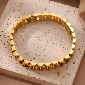 Detalle de pulsera de acero de titanio dorado con cristales rosas en eslabones curvos