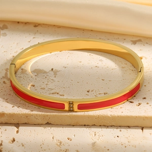 Close-up of 18k gold plated bangle with red enamel and three inset cubic zirconia