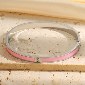 Detail of silver stainless steel bangle with pink enamel and three round zircon stones