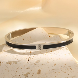 Close-up of a silver stainless steel hinge bangle with black enamel and three inset diamonds