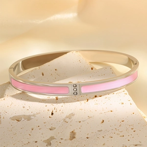 Detail of silver bangle featuring pink enamel inlay and three small crystals on travertine
