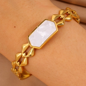 Primer plano de pulsera de acero bañada en oro 18K con nácar blanco y eslabones en X