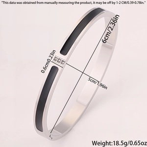 Detailed view of silver stainless steel bangle with black enamel and three small zircons