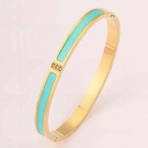 Detail view of gold-plated bangle featuring sky blue enamel and three inset crystals