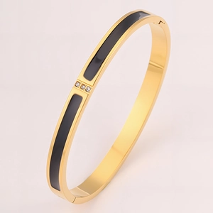 Detailed close-up of 18k gold plated stainless steel bangle with three clear zircons and black enamel