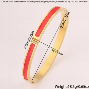 Macro shot of gold plated steel bangle featuring red enamel and three zircon stones