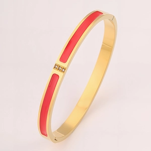 Detail of 18k gold plated stainless steel bangle with red enamel and three inset diamonds