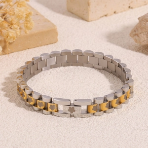 Macro detail of silver and gold watch-style steel bracelet with floral carvings