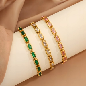 Detailed close-up of emerald, white, and pink zircon rectangle stones on gold bracelets