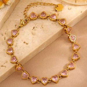 Detail of pink crystal heart bracelet in gold finish on a marble surface background
