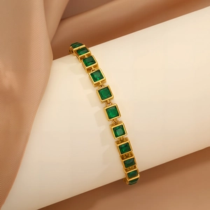 Detail showing gold chain bracelet with square green zircon stones on silk background