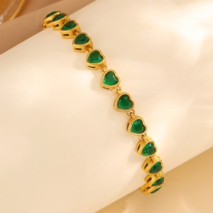 Close-up of heart-shaped emerald green zircon stones on a gold-plated link bracelet