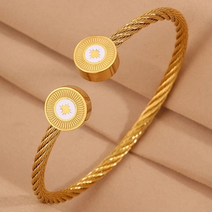Détail du bracelet câble doré avec des motifs d'étoiles gravés sur les embouts ronds
