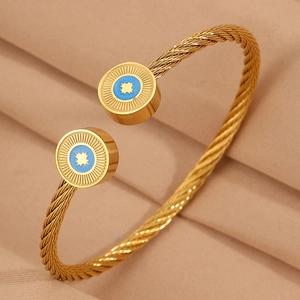 Détail d'un bracelet câble doré avec gravure d'étoile et breloque en émail bleu