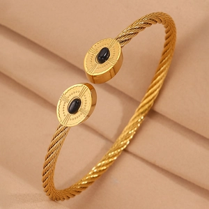 Détail du bracelet ouvert en câble doré avec pierre noire et gravure à rayons de soleil
